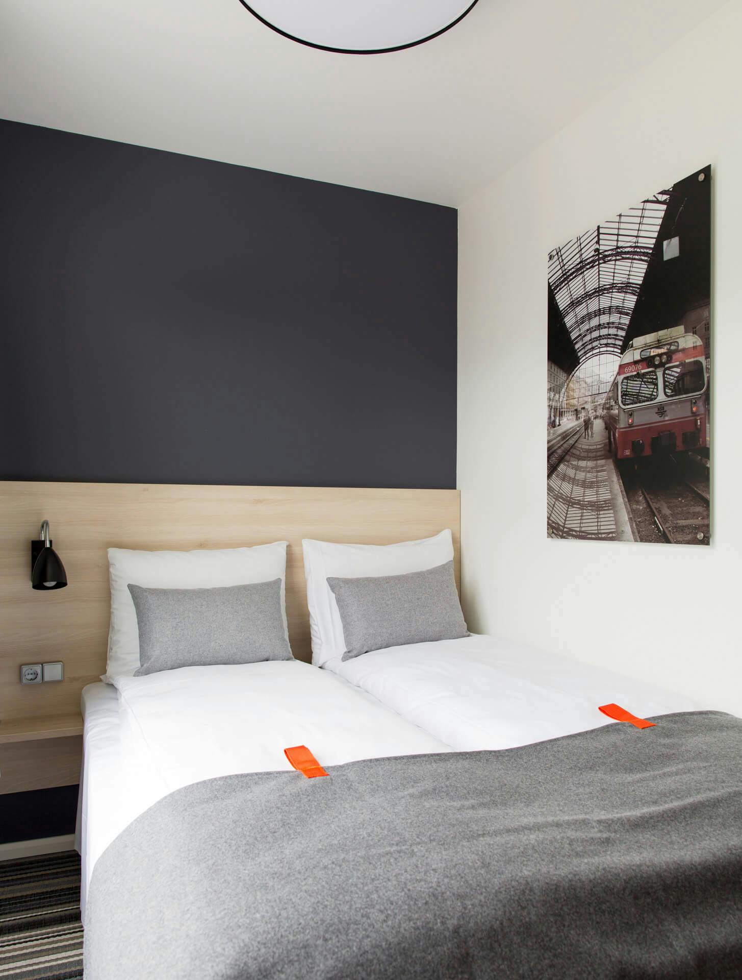Image of a room with a double bed, reading lamp and a picture on the wall