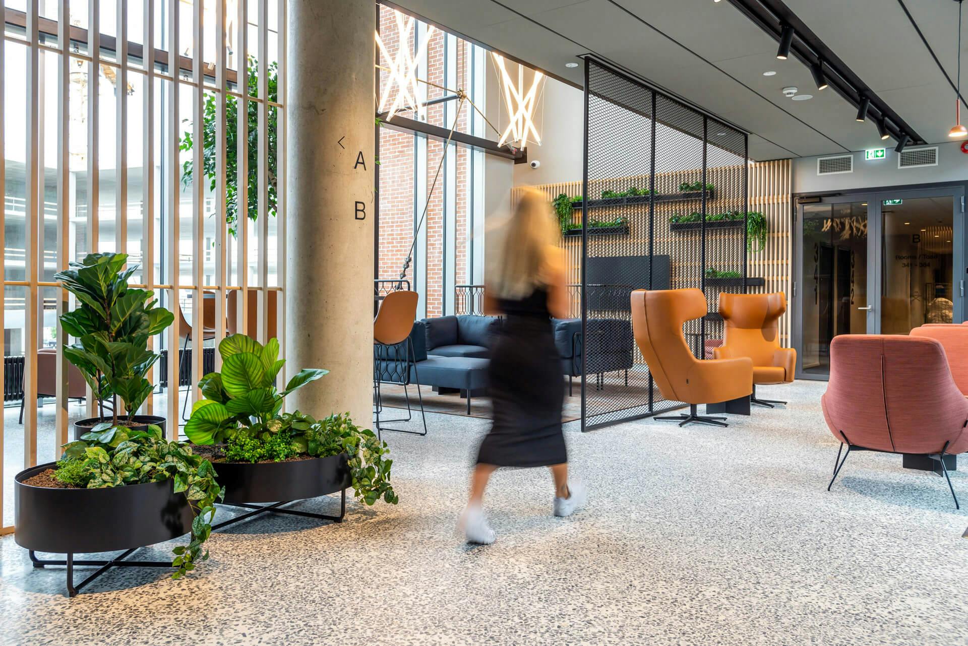 Woman walking in the lobby area, seating groups, plants